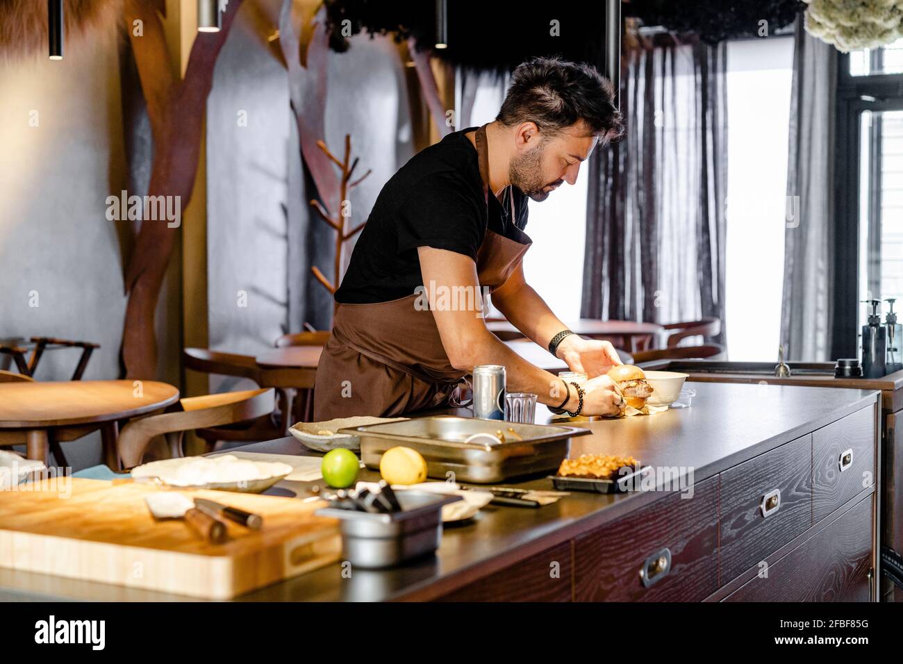 Male chef preparing food on kitchen island at restaurant Stock Photo