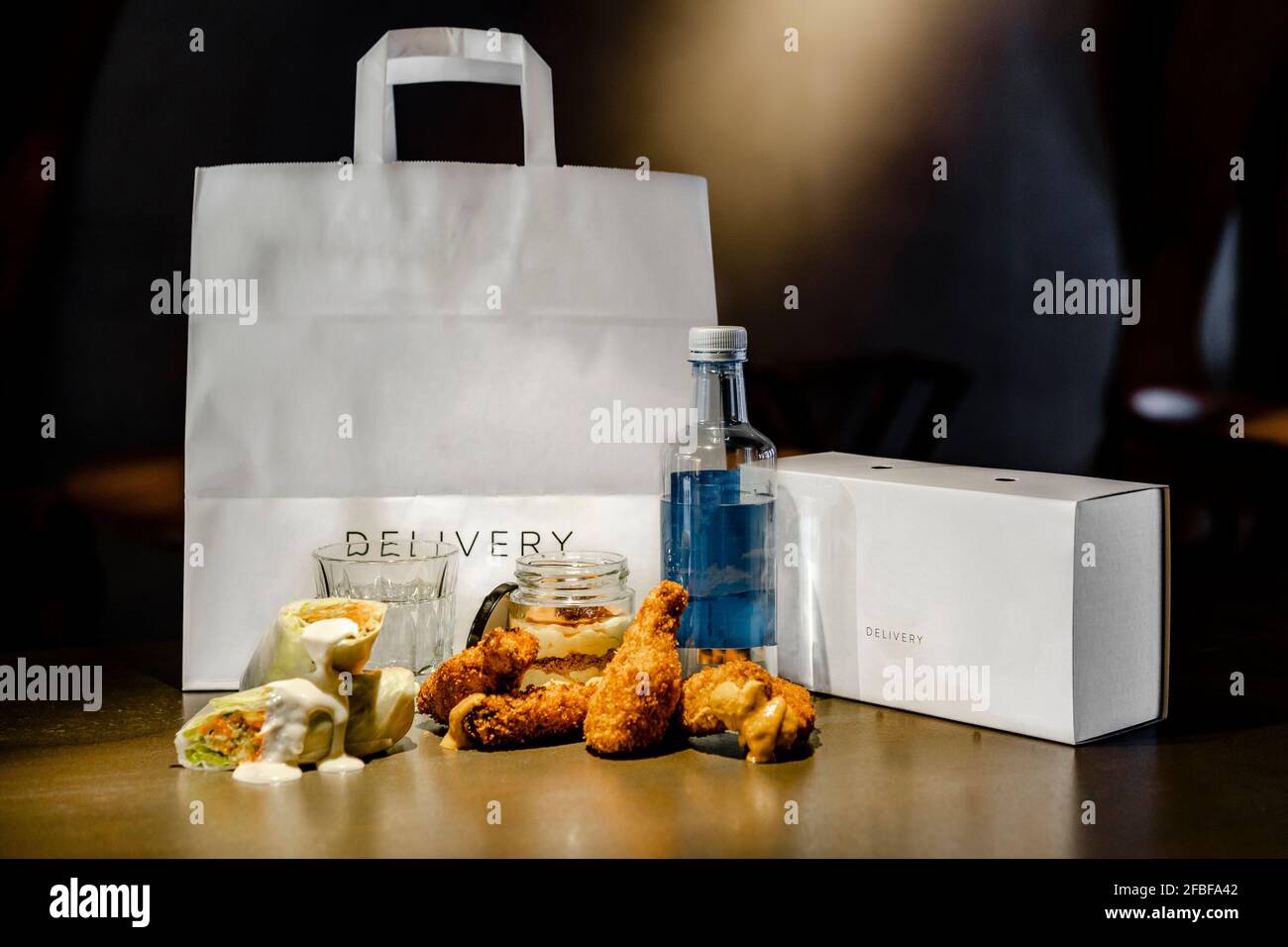 Chicken wings and wrap sandwich by delivery bag and box on kitchen island Stock Photo