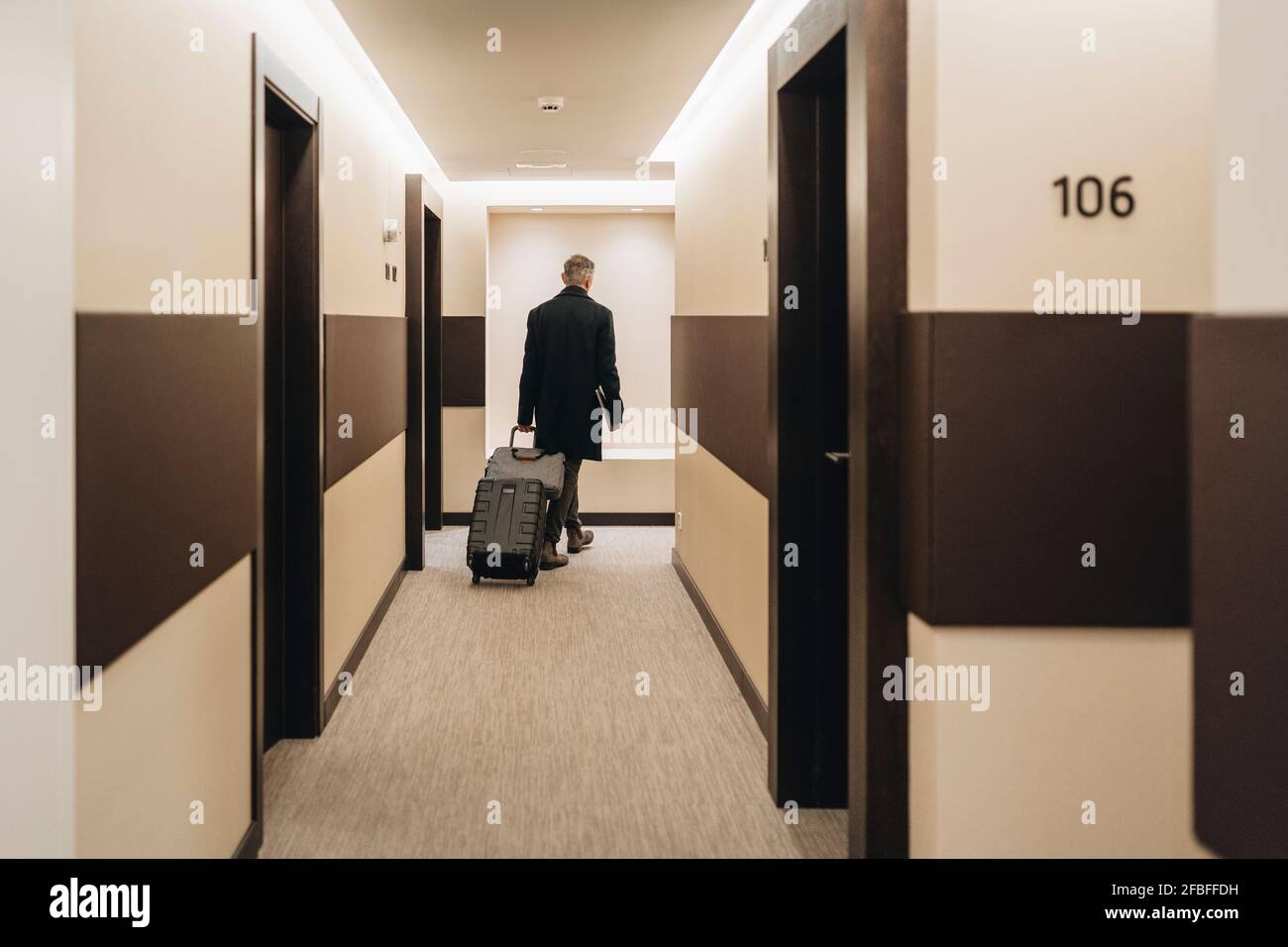 Businessman walking with briefcase and luggage at hotel corridor Stock Photo