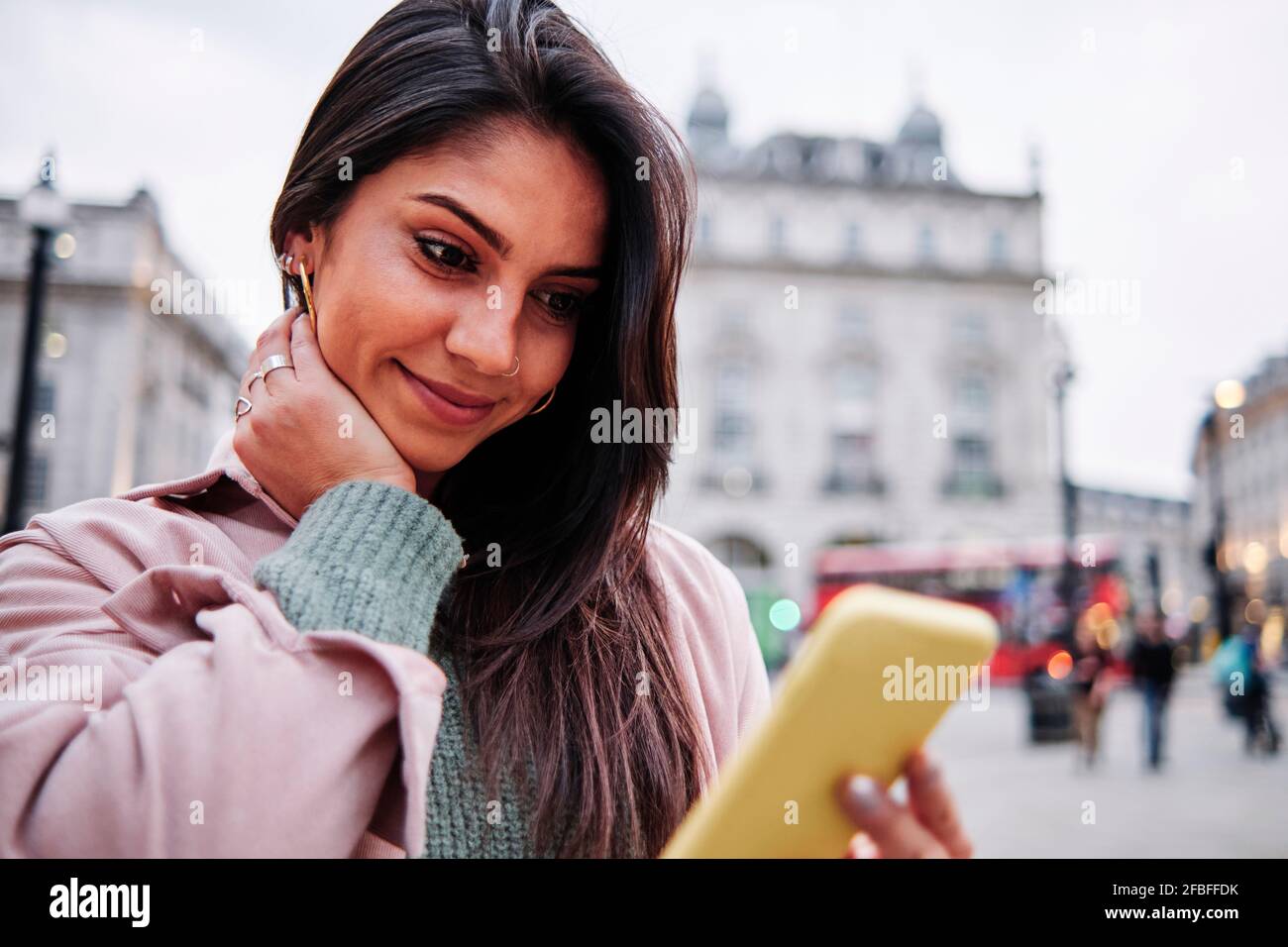 Smiling woman looking at mobile phone in city Stock Photo