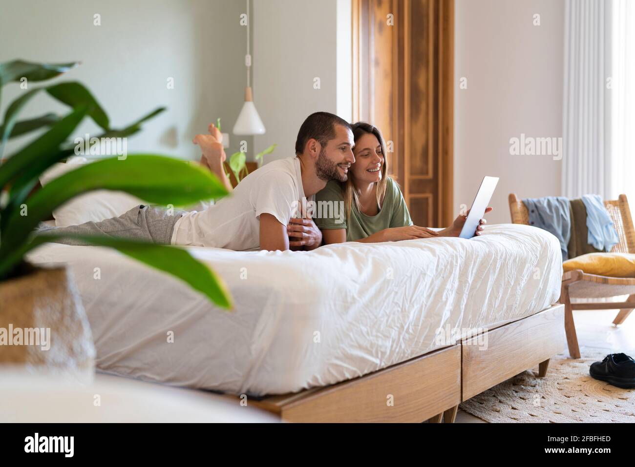 Young couple using laptop while lying on bed in bedroom at home Stock ...