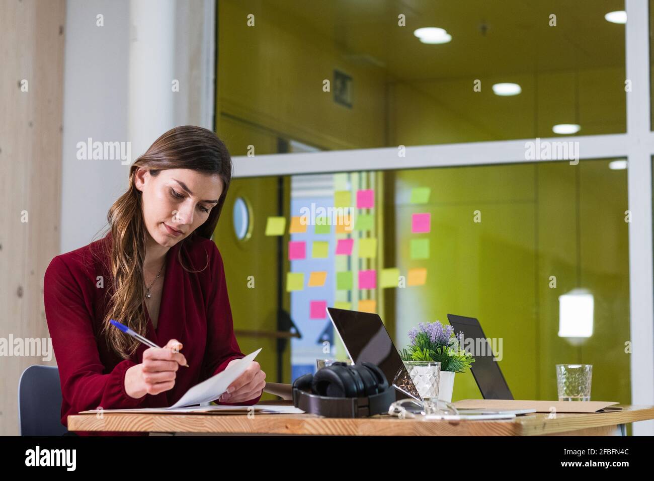 Young female entrepreneur working by desk at workplace Stock Photo