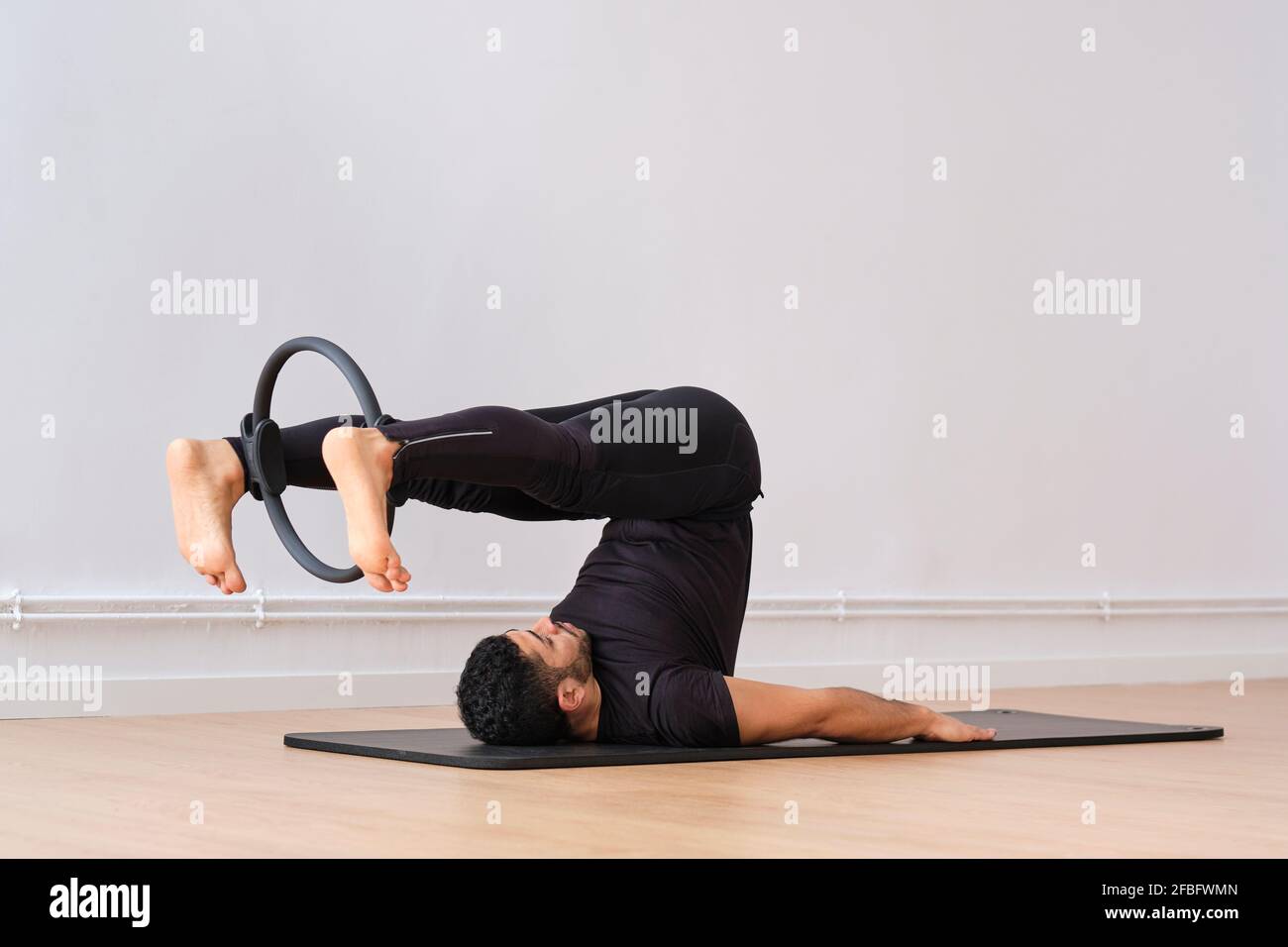 Man exercising with pilates ring by wall in exercise room Stock Photo Alamy