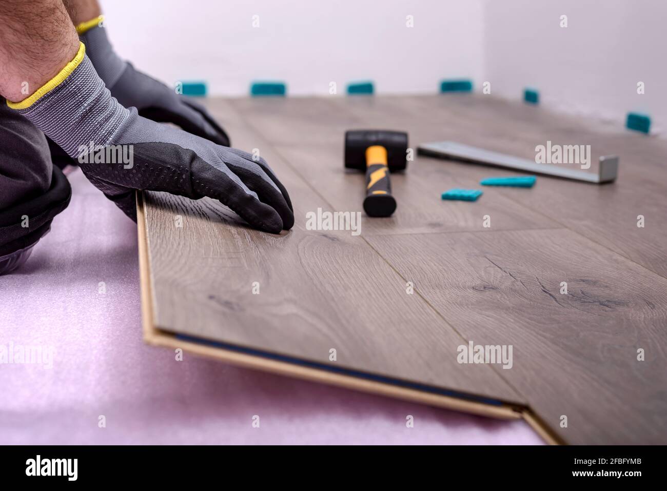 Male hands is laying wooden panel of laminate floor in the room. Selective focus. Stock Photo