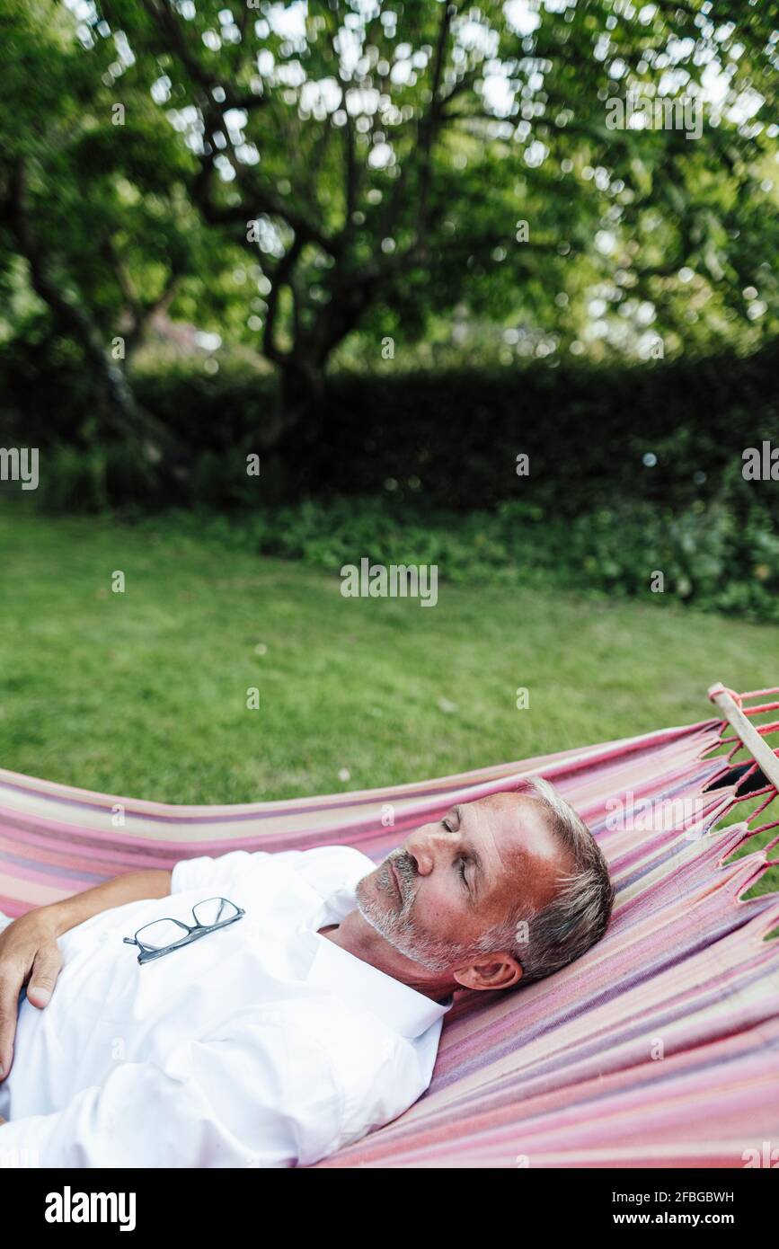 Mature man sleeping on hammock in backyard Stock Photo