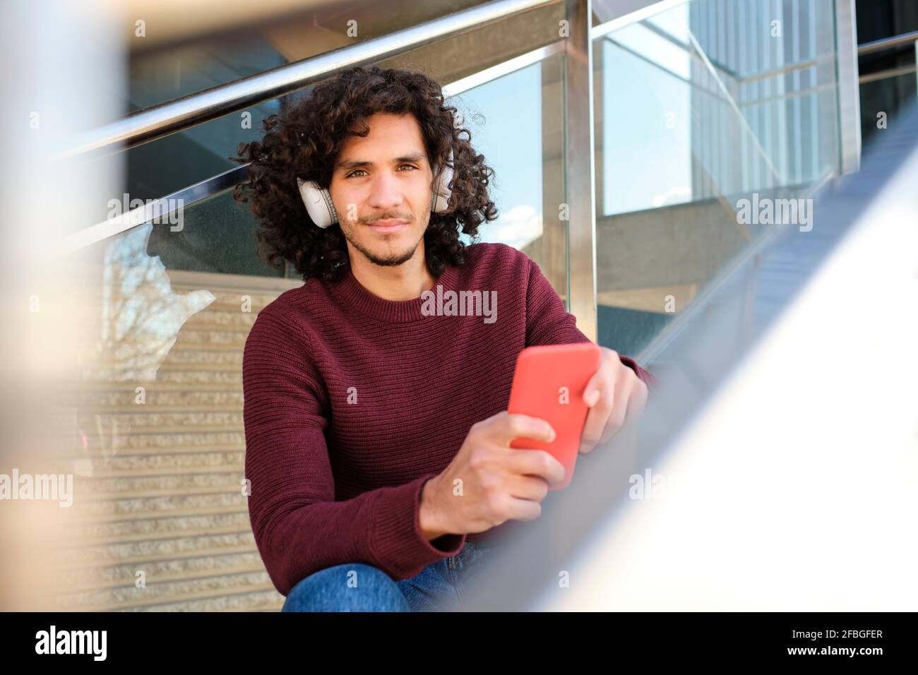 Caucasian young man with headphones holding mobile phone at structure Stock Photo