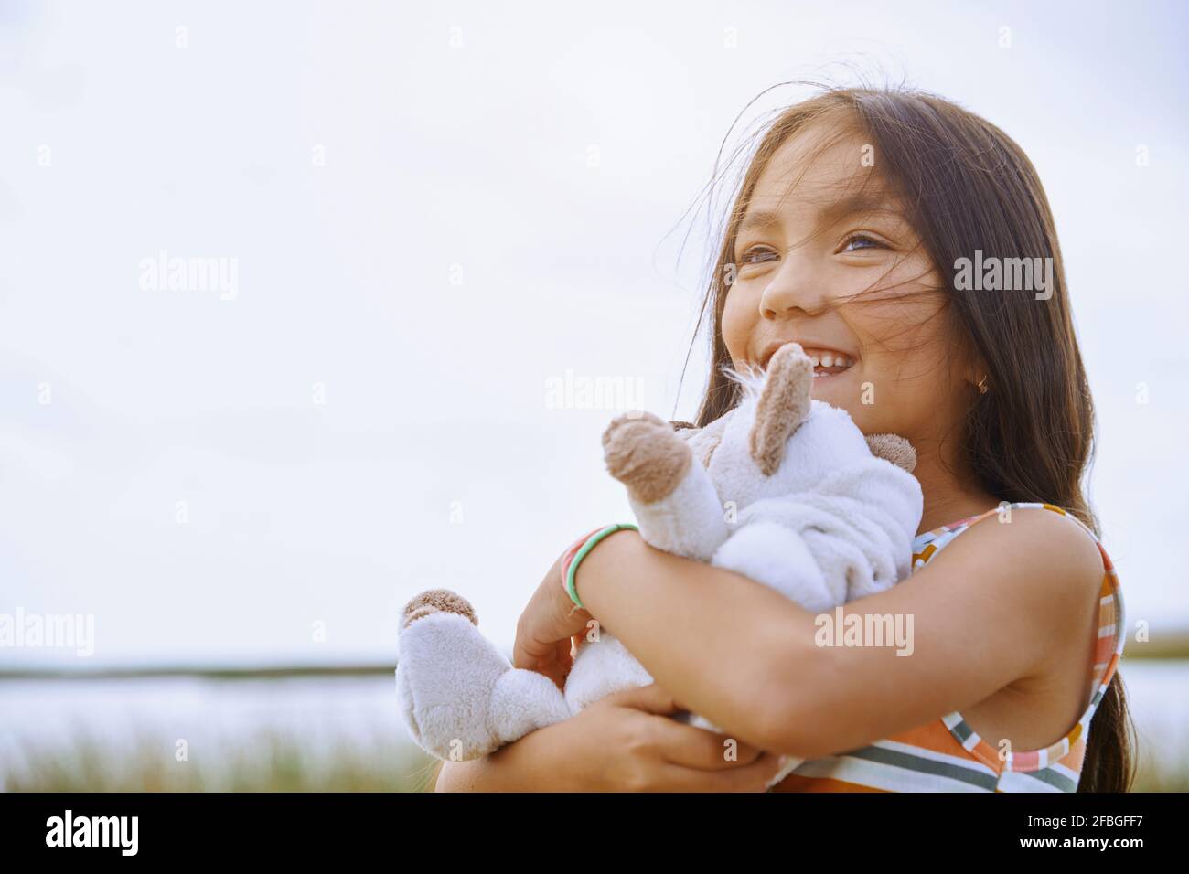 Cute girl looking away while holding stuffed teddy bear Stock Photo - Alamy