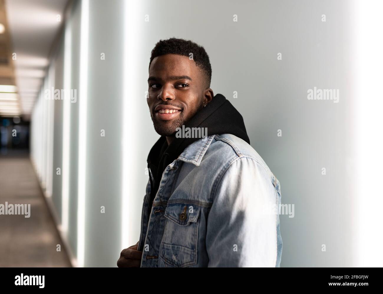Young man wearing denim jacket in corridor Stock Photo