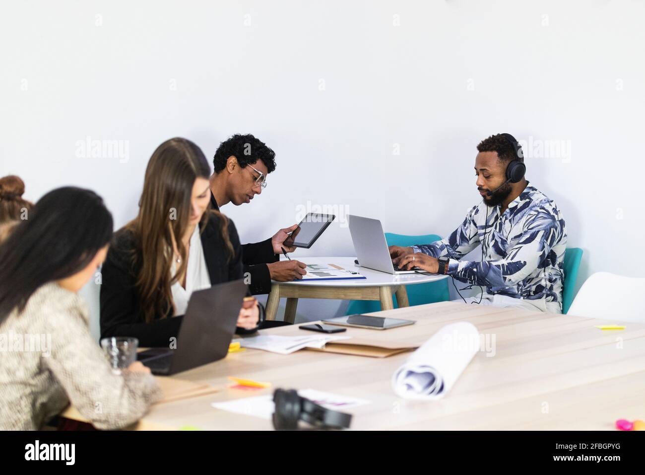 Businessmen working while sitting with colleagues in creative office Stock Photo