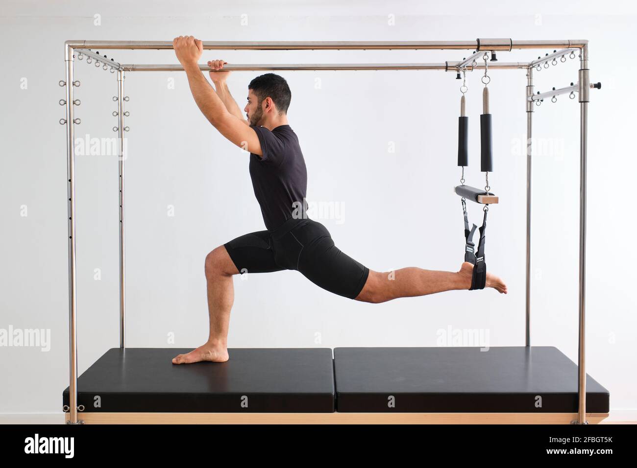 Mid adult male athlete practicing pilates on trapeze table in exercise room Stock Photo