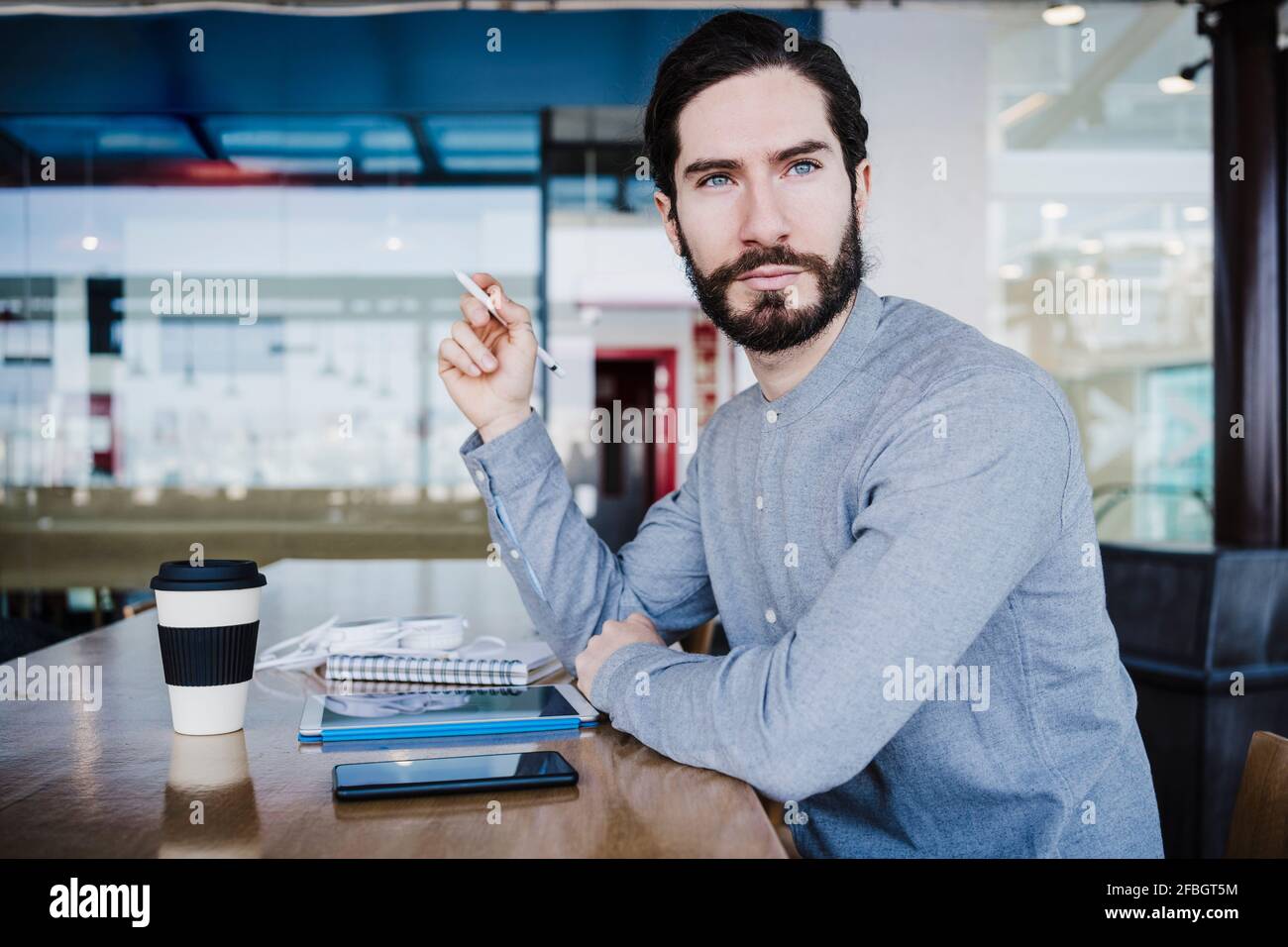 Thoughtful male businessperson looking away while sitting by desk at work place Stock Photo