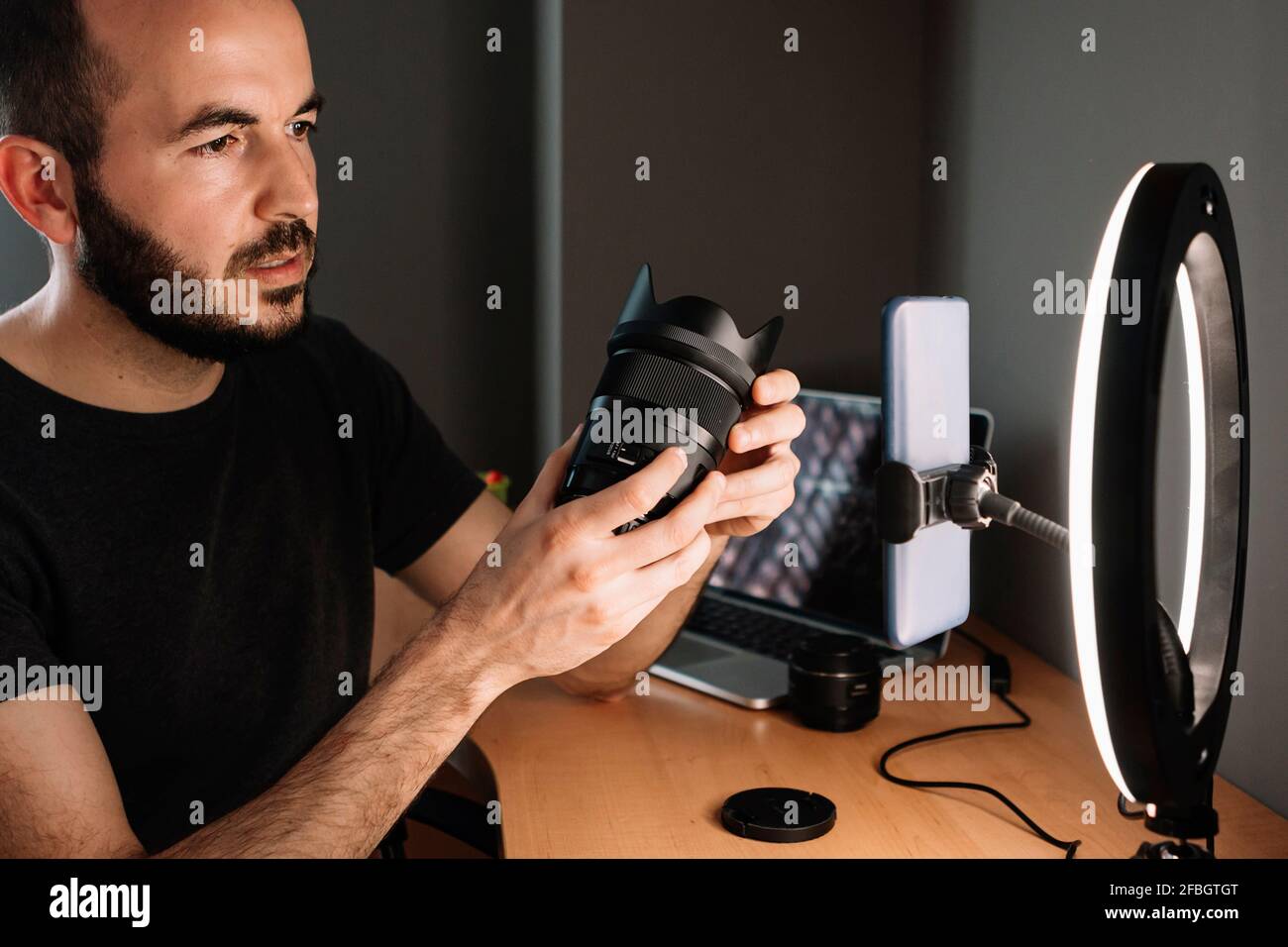Vlogger with podcasting looking at illuminated camera flash with phone at studio Stock Photo