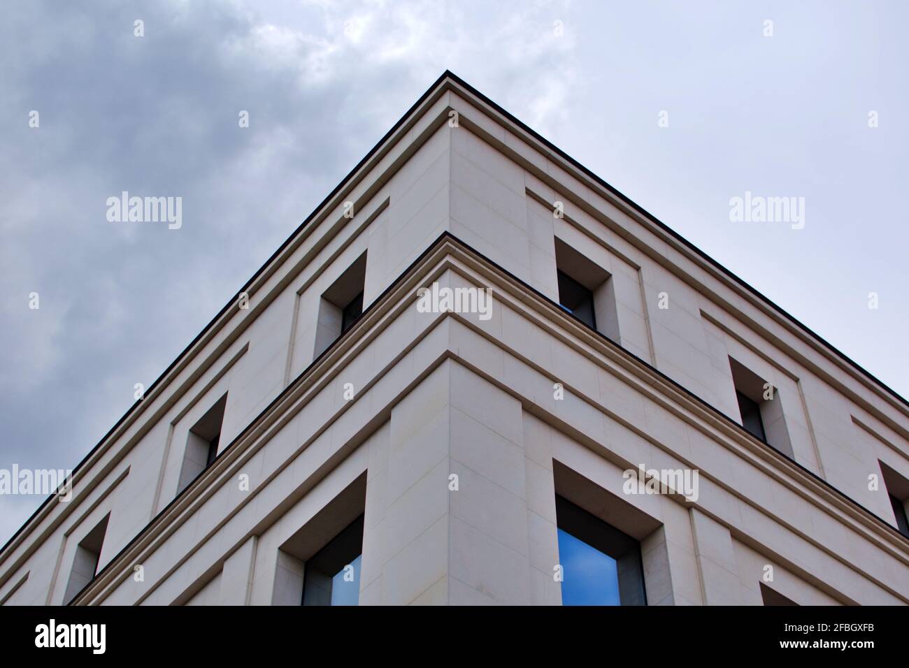 Building facade. Corner of house with windows by the edges against stormy sky Stock Photo