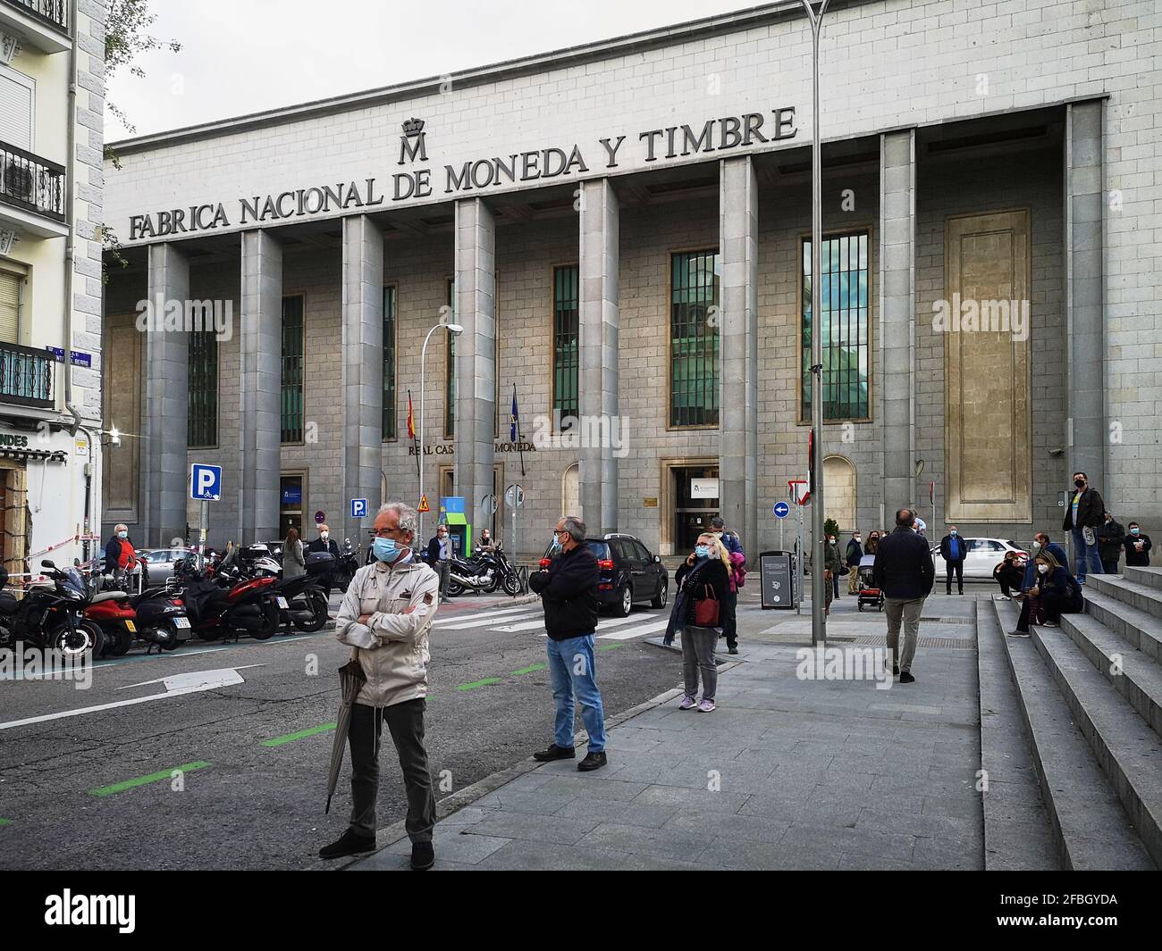 Madrid, Spain. April 23, 2021: Mature people wearing face protective masks in front of the 'Fabrica Nacional de Moneda y Timbre'. Stock Photo