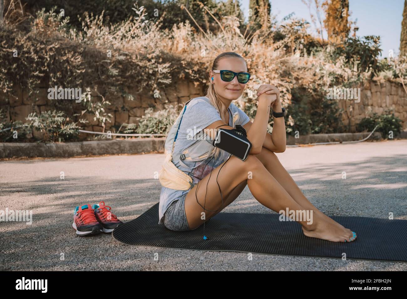 Sportive Woman Resting on the Mat in the Park after Workout. Enjoying Outdoors Sport. Energy Life. Healthy Lifestyle. Stock Photo