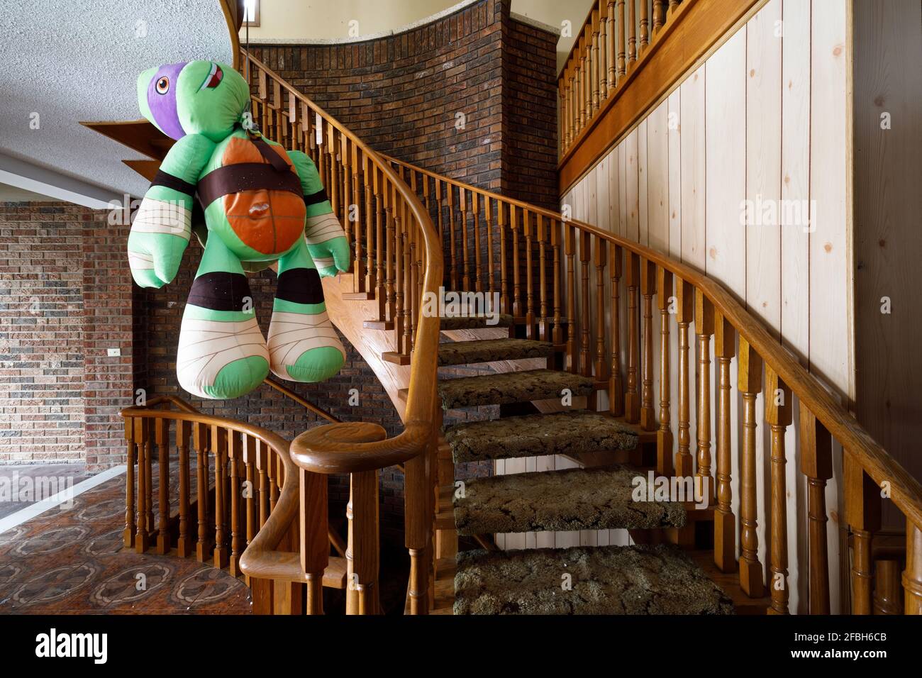 A Donatello Teenage Mutant Ninja Turtle stuffed toy hanging from a  staircase by the neck Stock Photo - Alamy