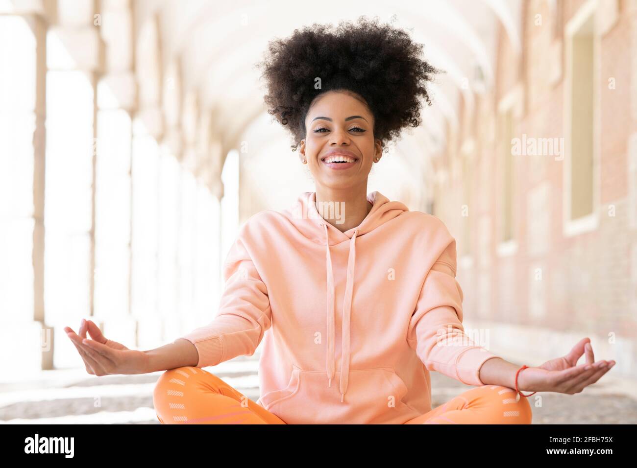 Happy afro woman meditating during sunny day Stock Photo