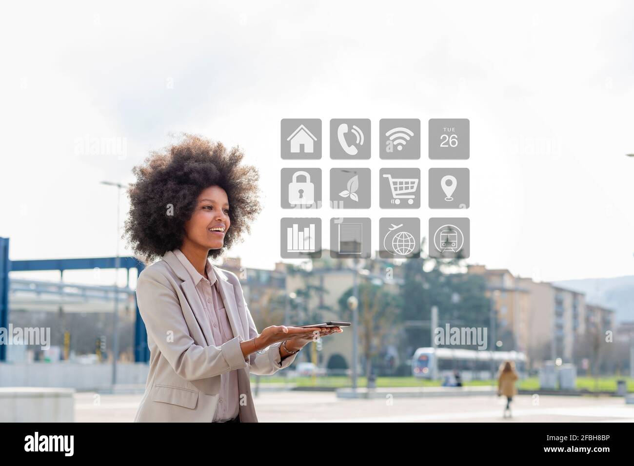 Female entrepreneur looking at app icon while holding mobile phone in city Stock Photo