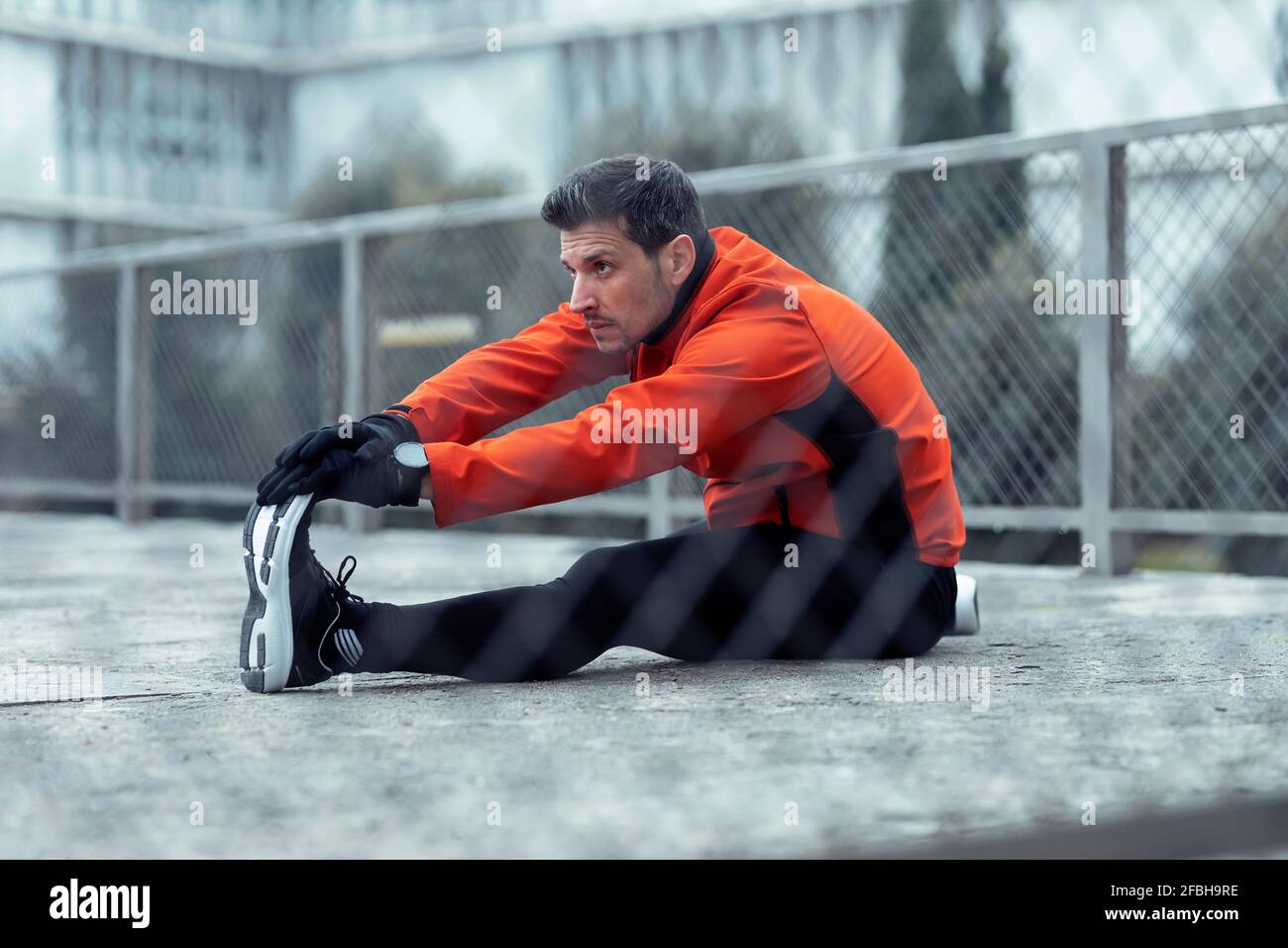Athletic man doing stretching exercise in park Stock Photo