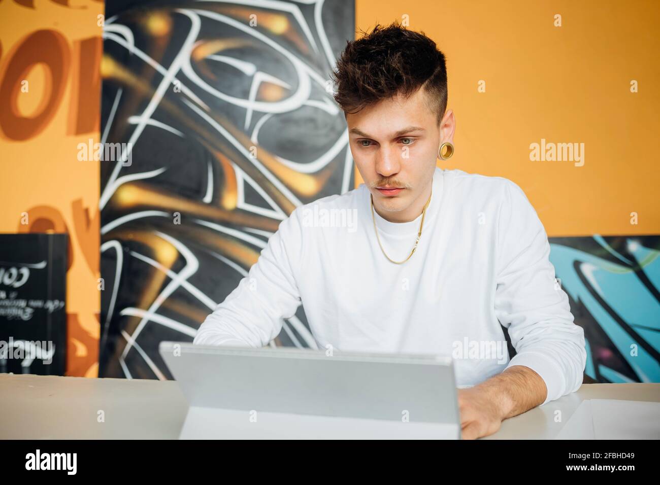 Young hipster man working while using laptop in studio Stock Photo