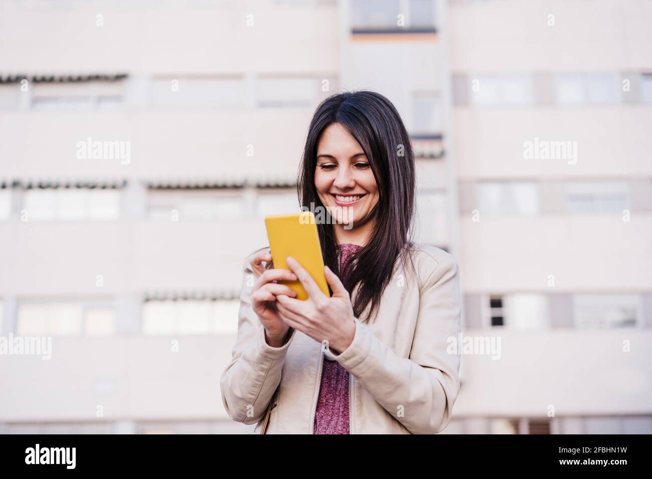 Contented woman using mobile phone while smiling Stock Photo