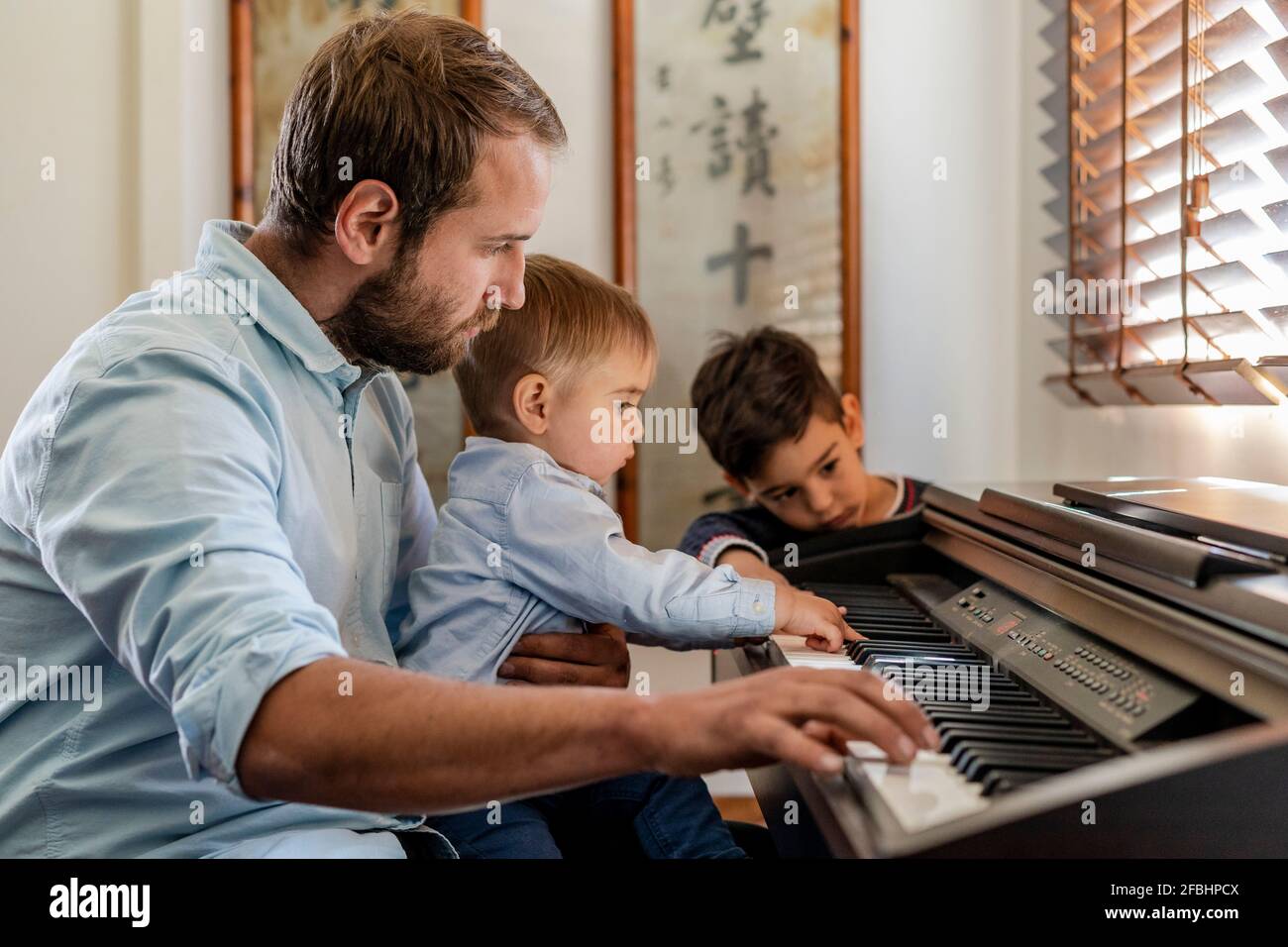 Father teaching piano to sons at home Stock Photo Alamy