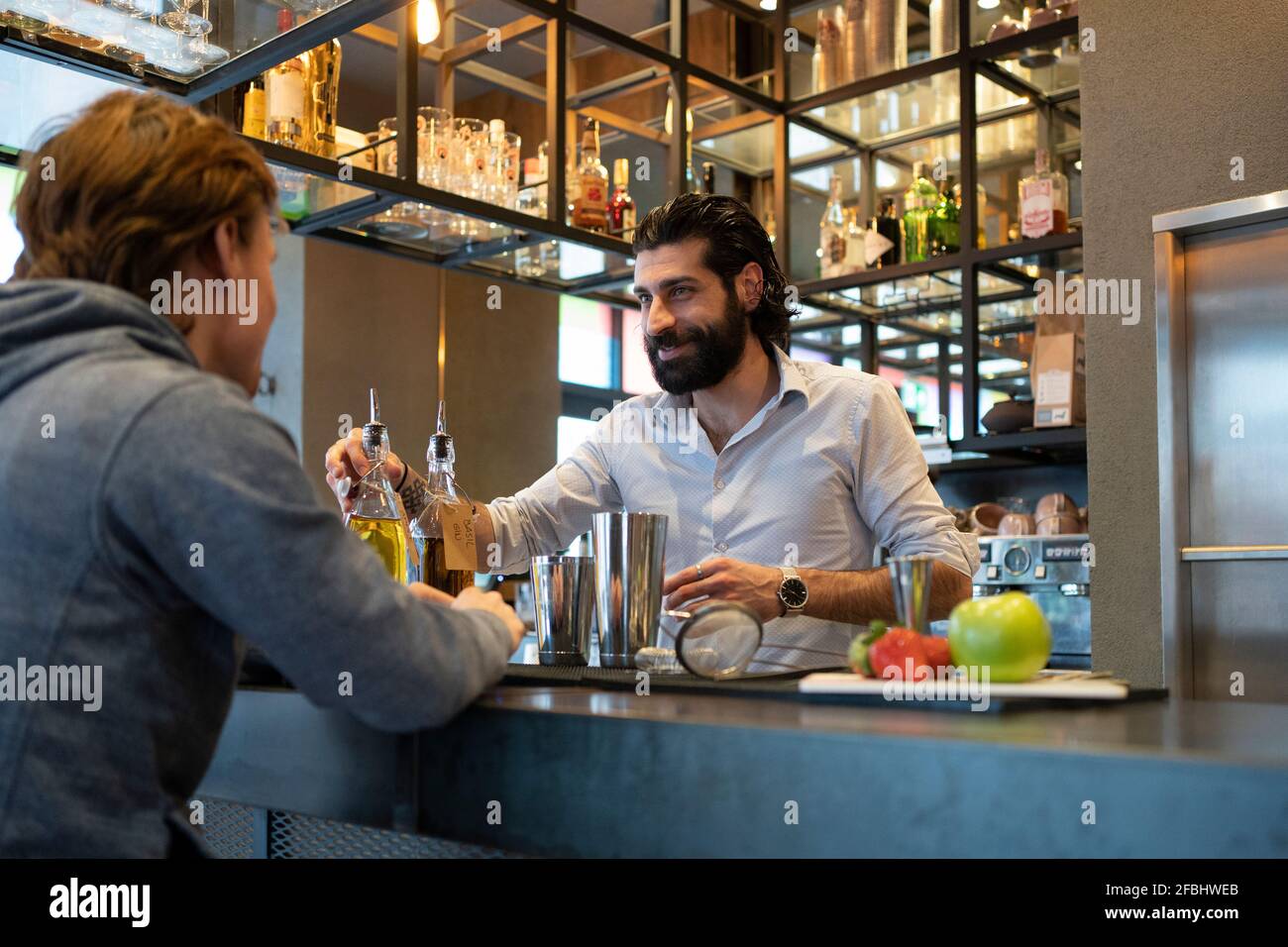 Smiling bartender serving alcohol to customer at bar counter Stock Photo Alamy