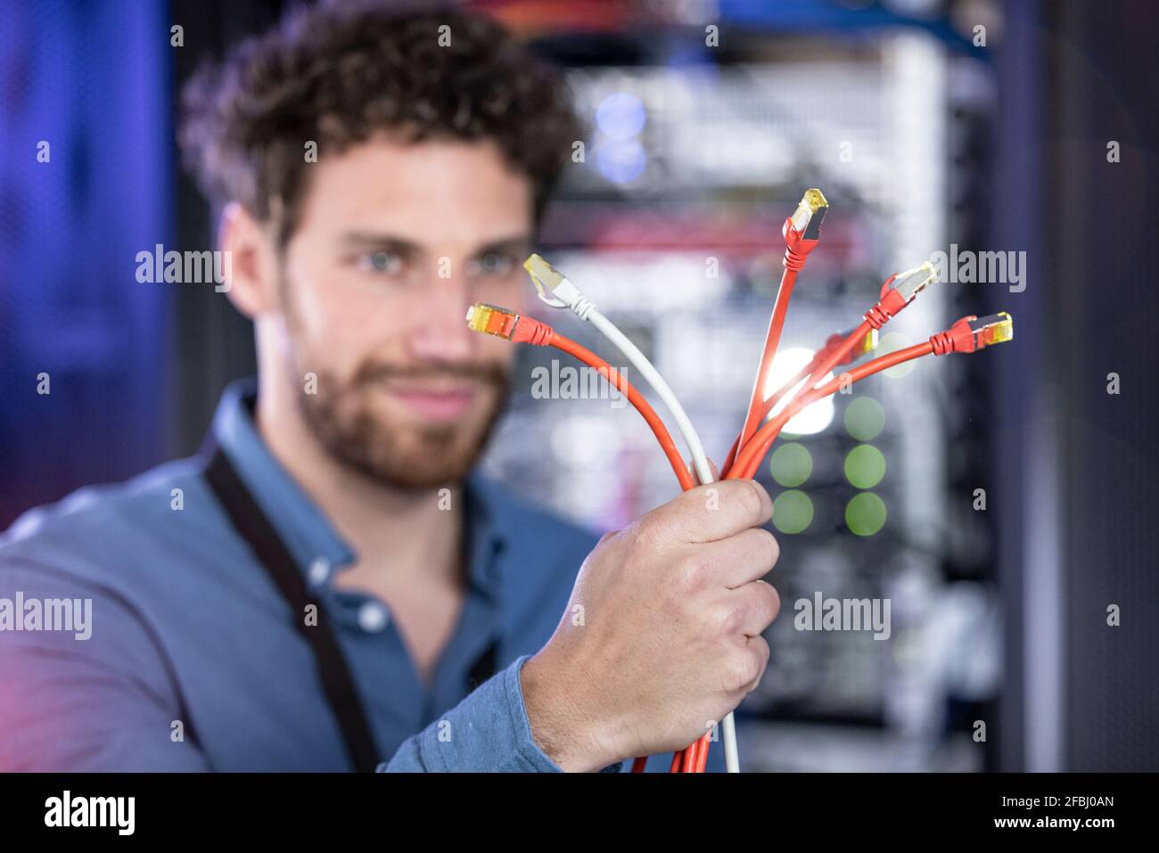 Male IT engineer holding patch cord cables in server room Stock Photo