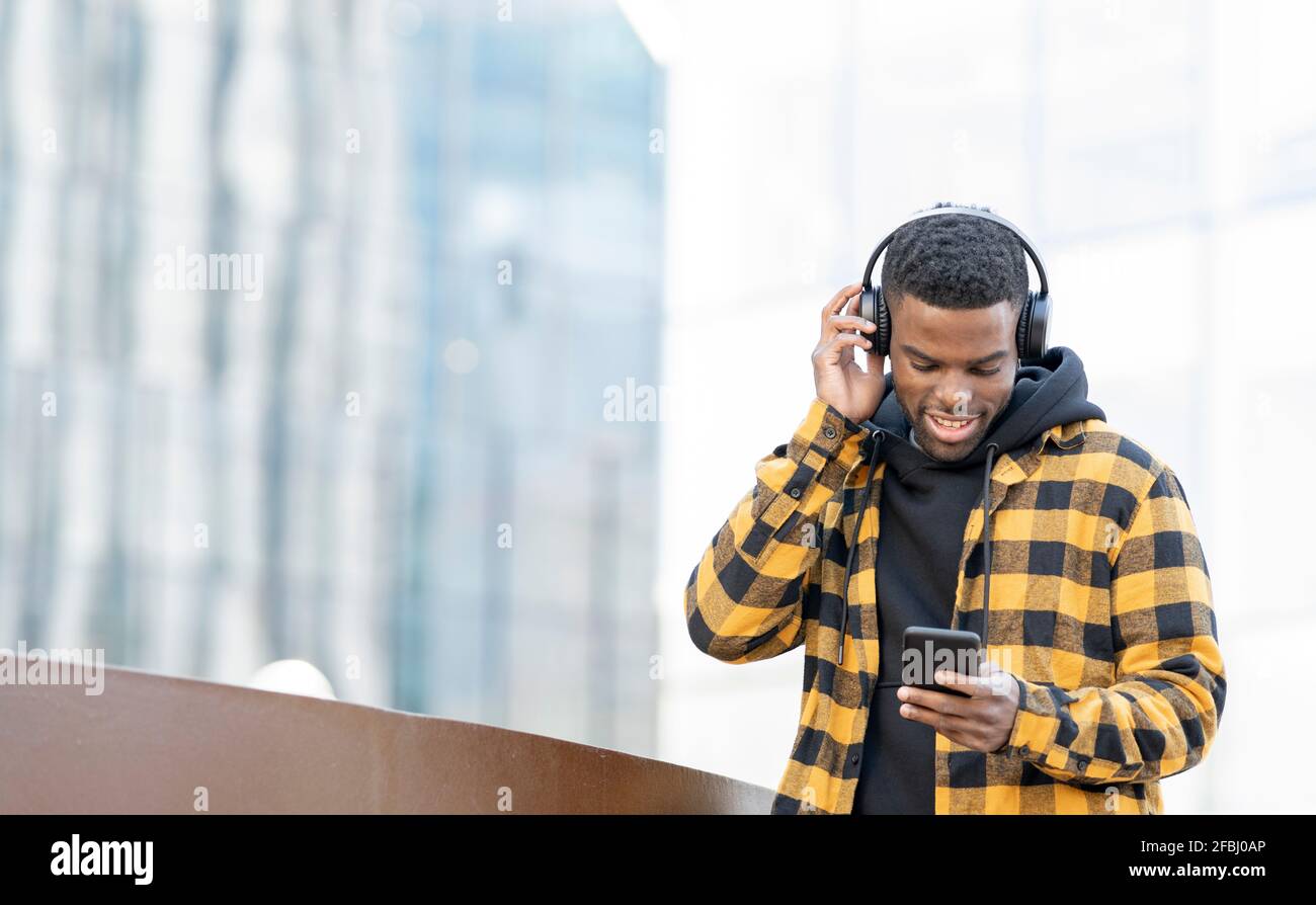 Man wearing headphones while using smart phone Stock Photo