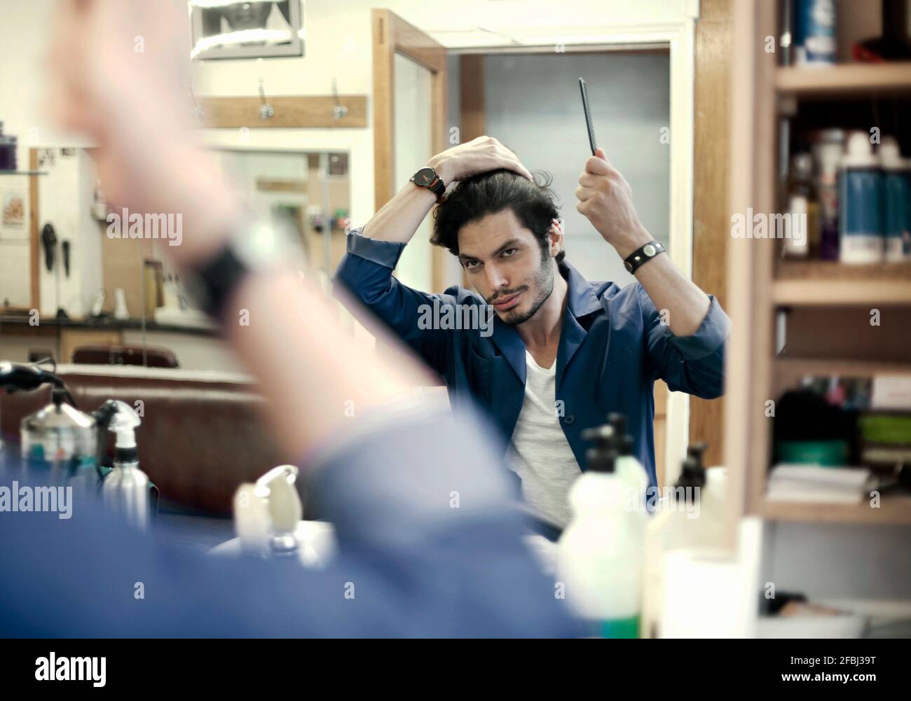 Portrait of barber fixing hair in front of mirror in barber shop Stock Photo Alamy