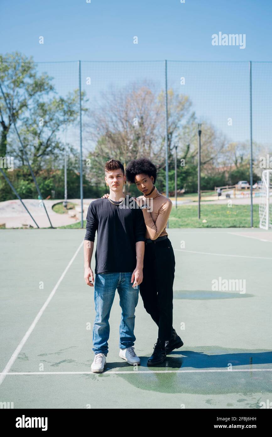 Multi ethnic couple standing at sports court during sunny day Stock Photo