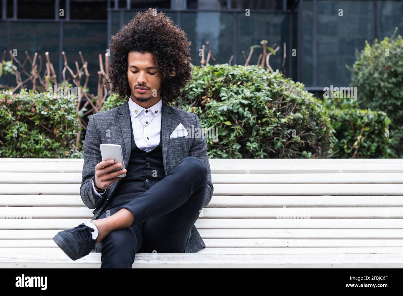 Handsome young businessman using mobile phone on bench Stock Photo
