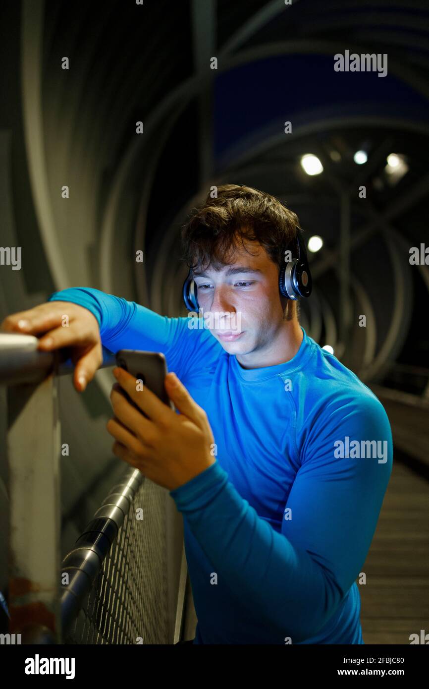 Athletes wearing headphones while using smart phones on footbridge Stock Photo