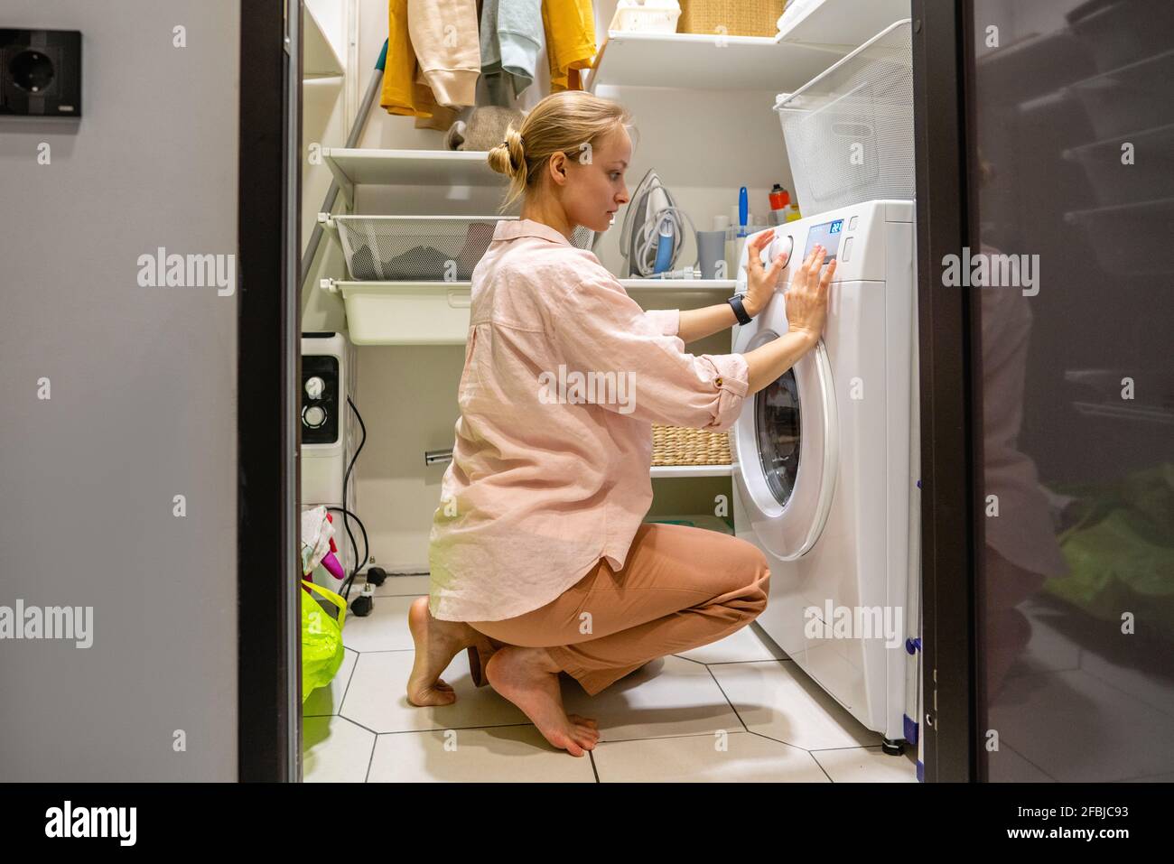 Young woman operating washing machine at home Stock Photo