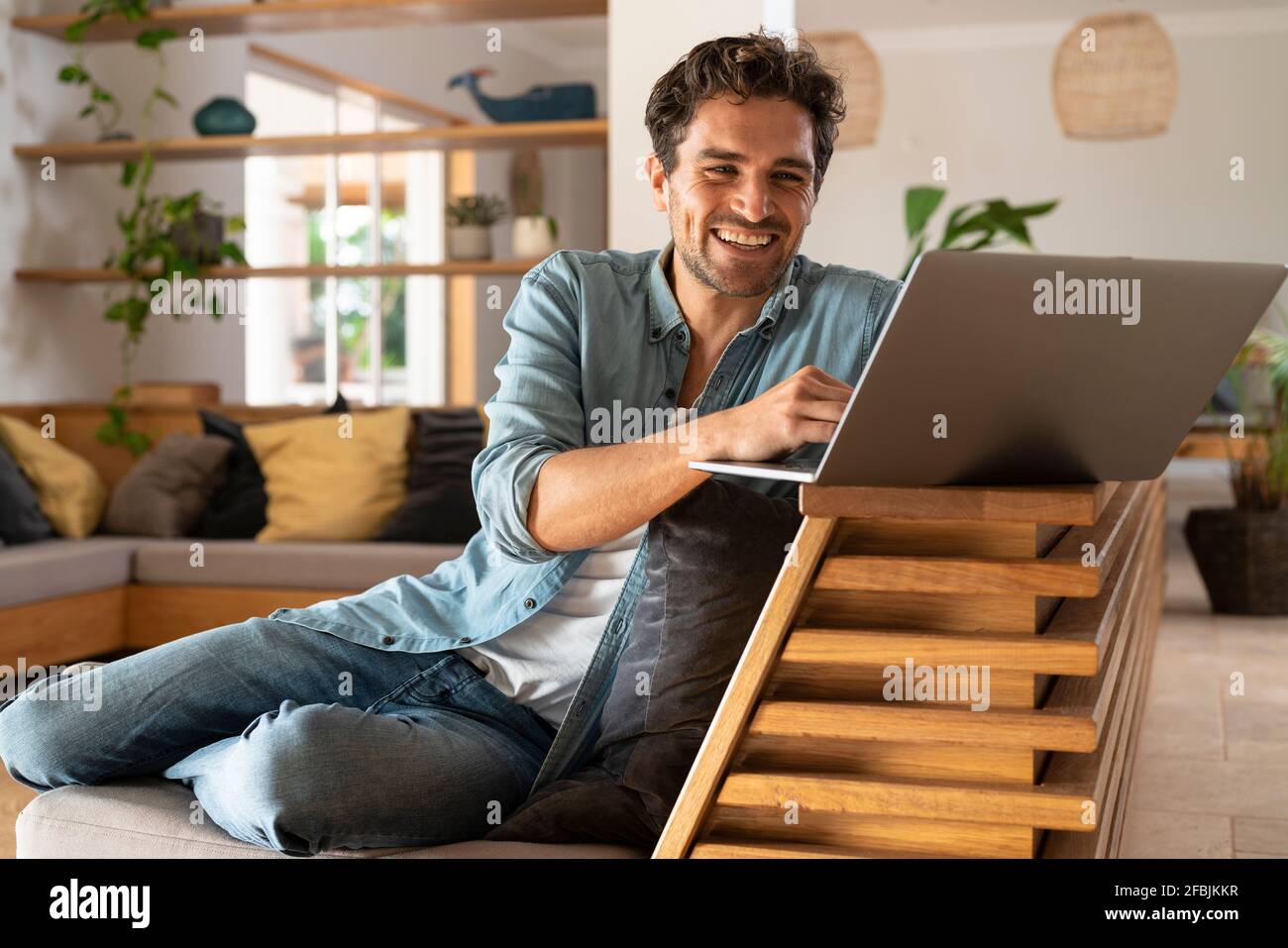 Happy male freelancer using laptop while sitting at home Stock Photo