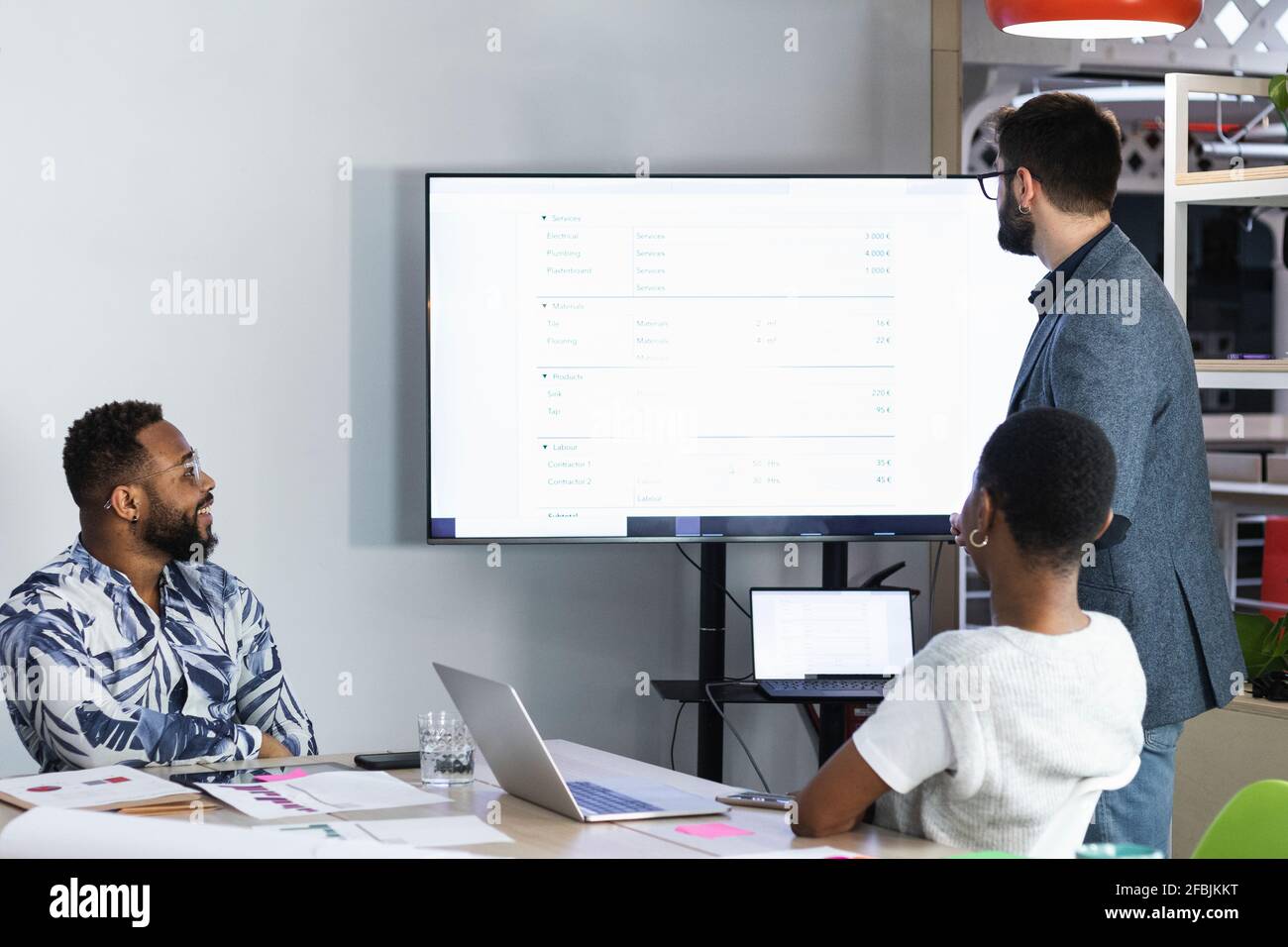 Entrepreneurs analyzing data over television while working in meeting Stock Photo