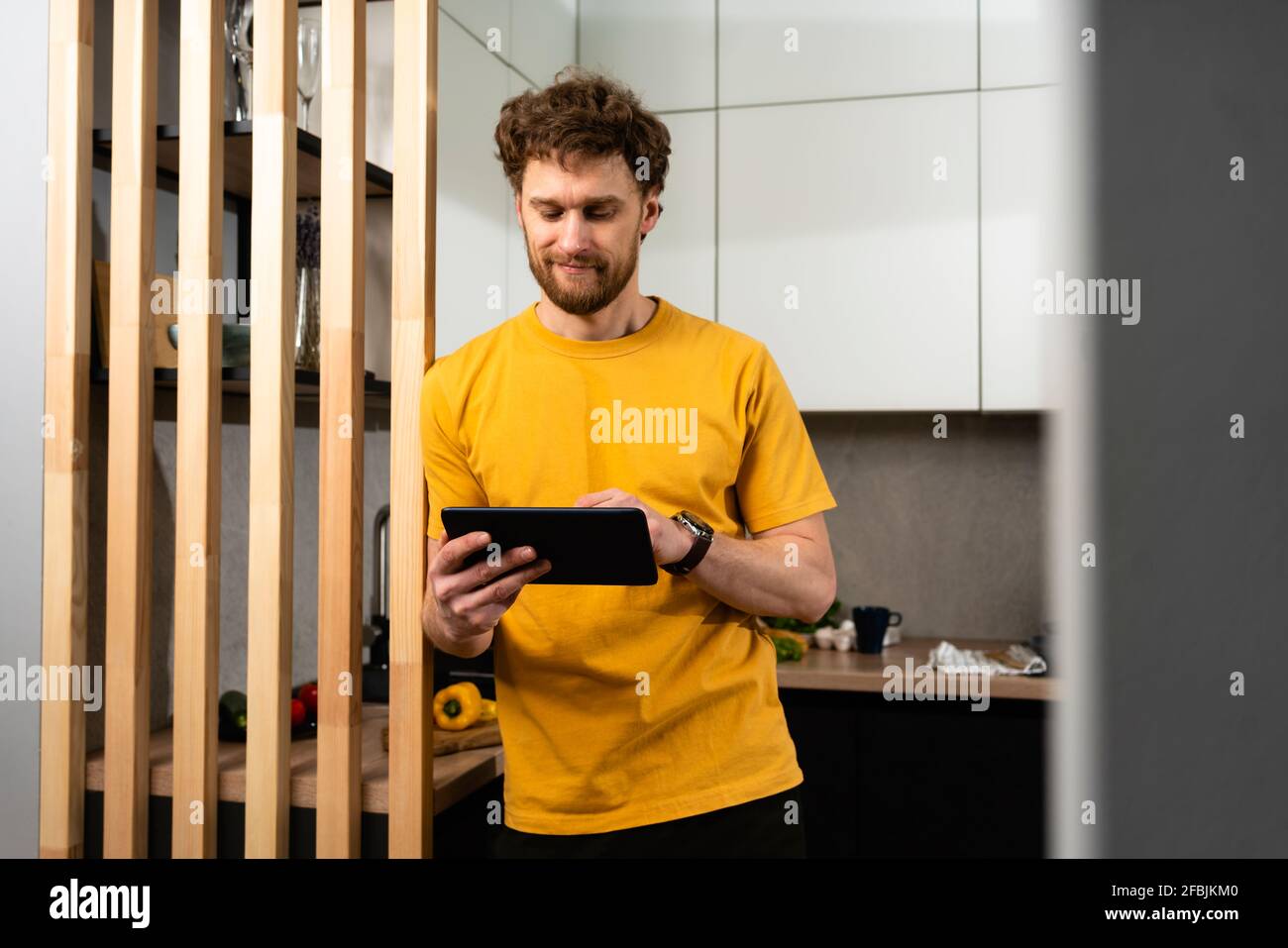 Handsome man using digital tablet while standing in domestic kitchen Stock Photo
