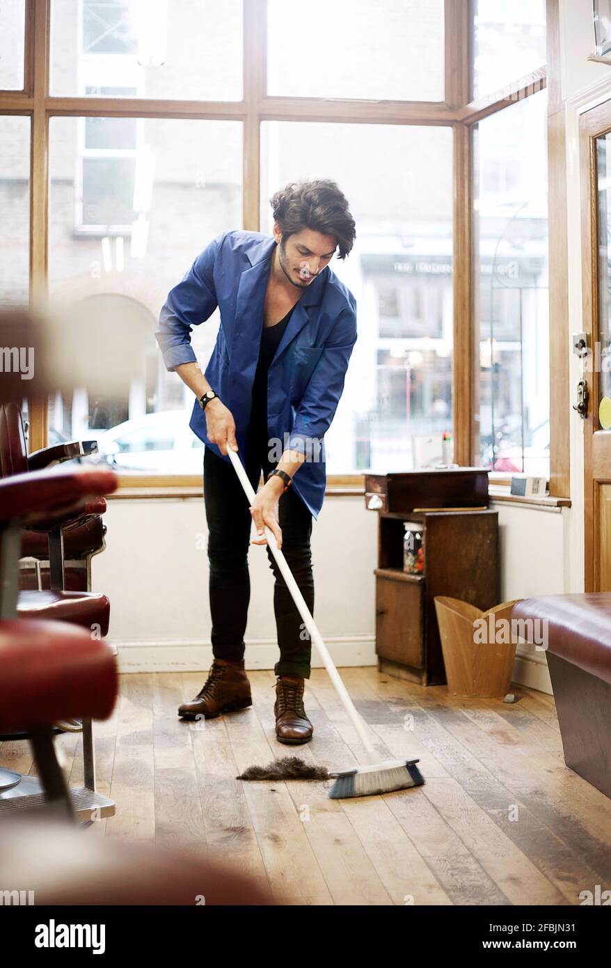 Barber sweeping floor in barber shop Stock Photo