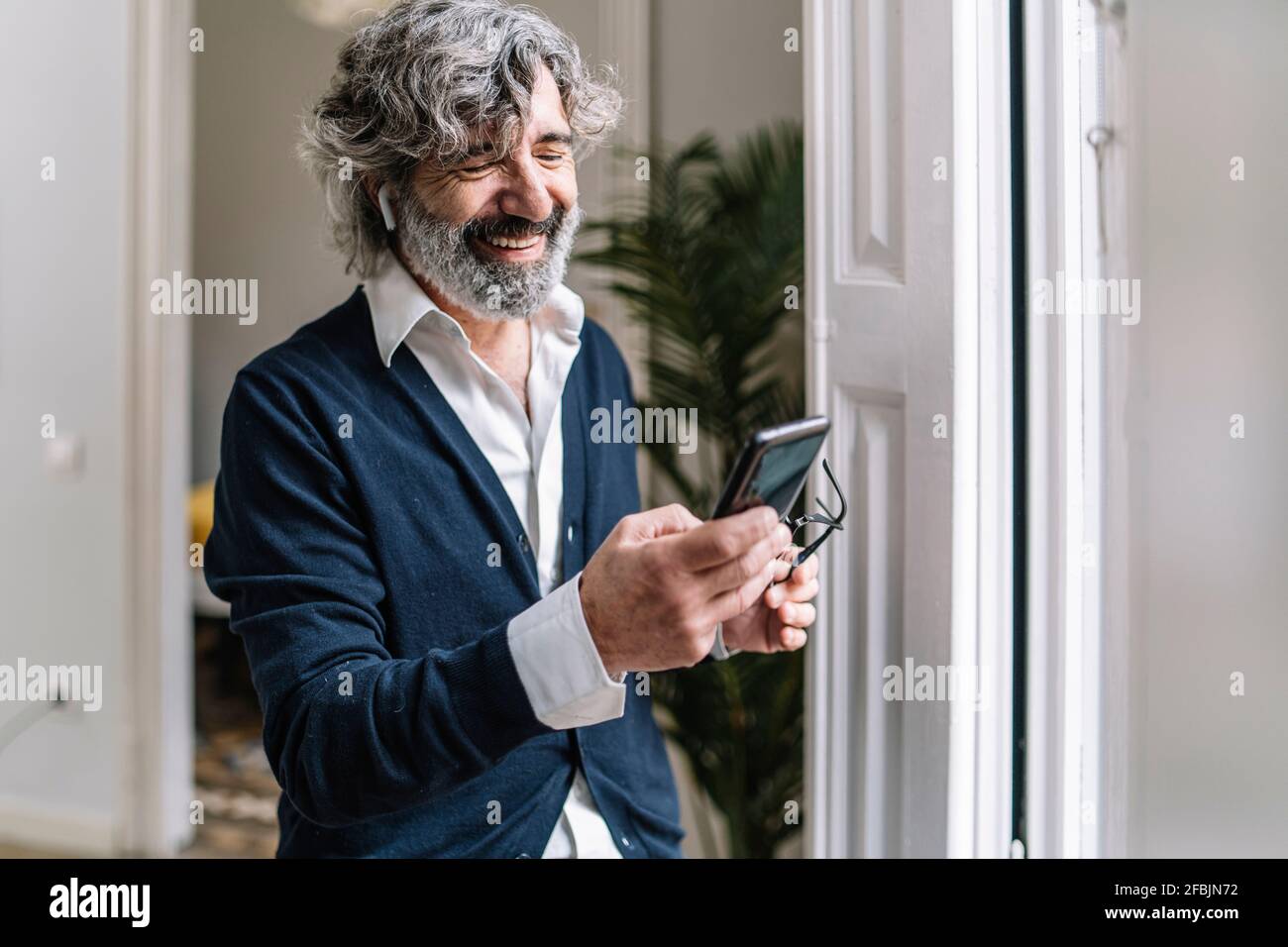 Smiling handsome man using smart phone at home Stock Photo