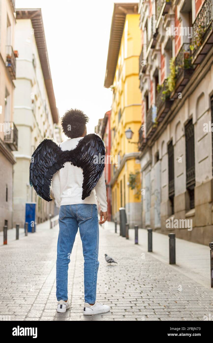 Man with angel wings standing outside building Stock Photo