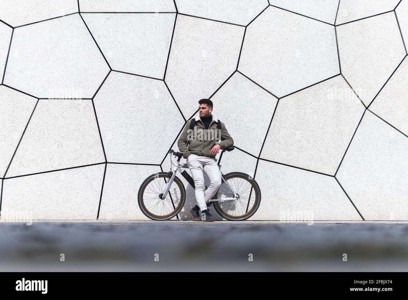 Young man leaning on bicycle while looking away Stock Photo