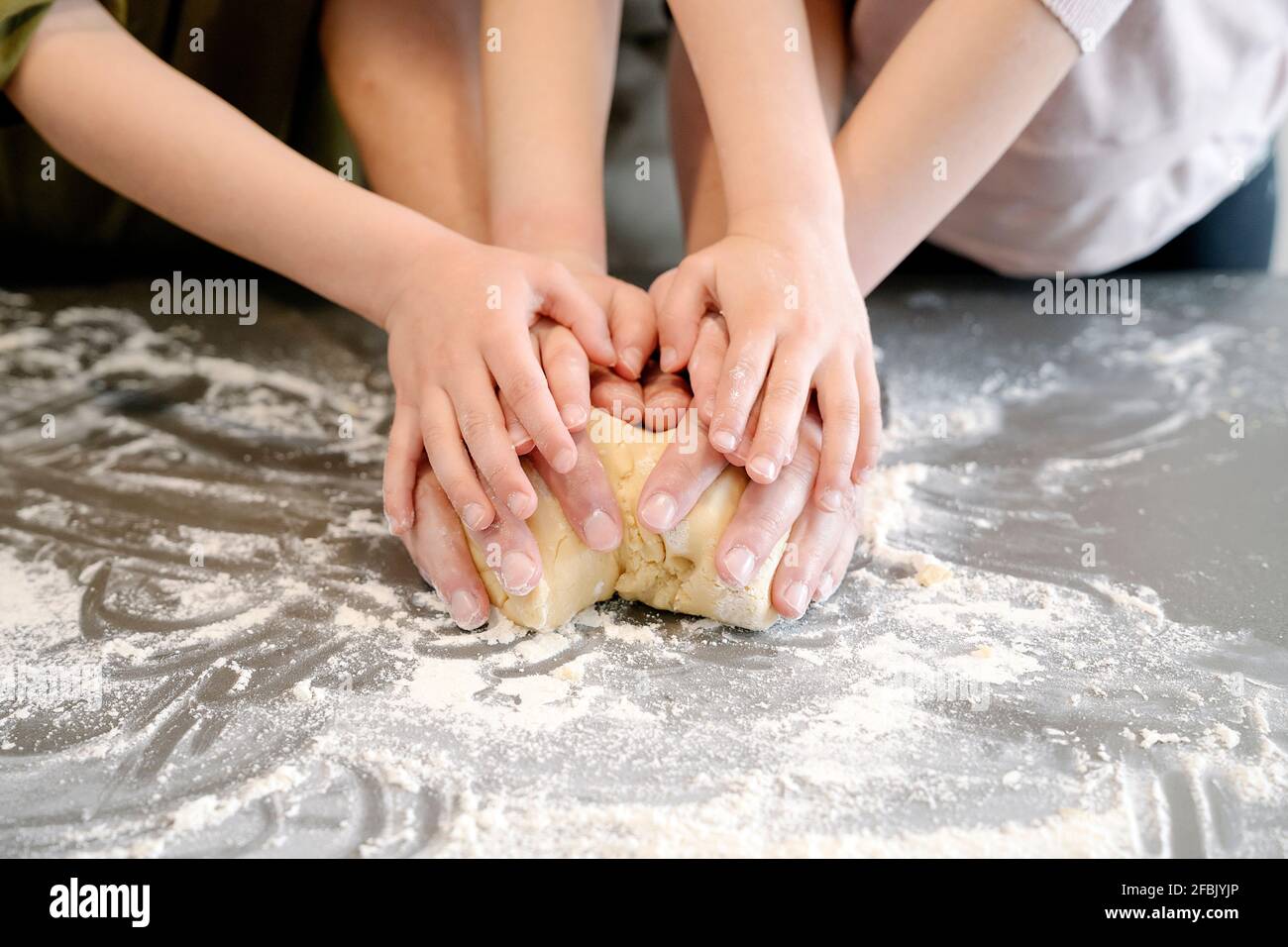 Father and children kneading dough together on kitchen island Stock Photo
