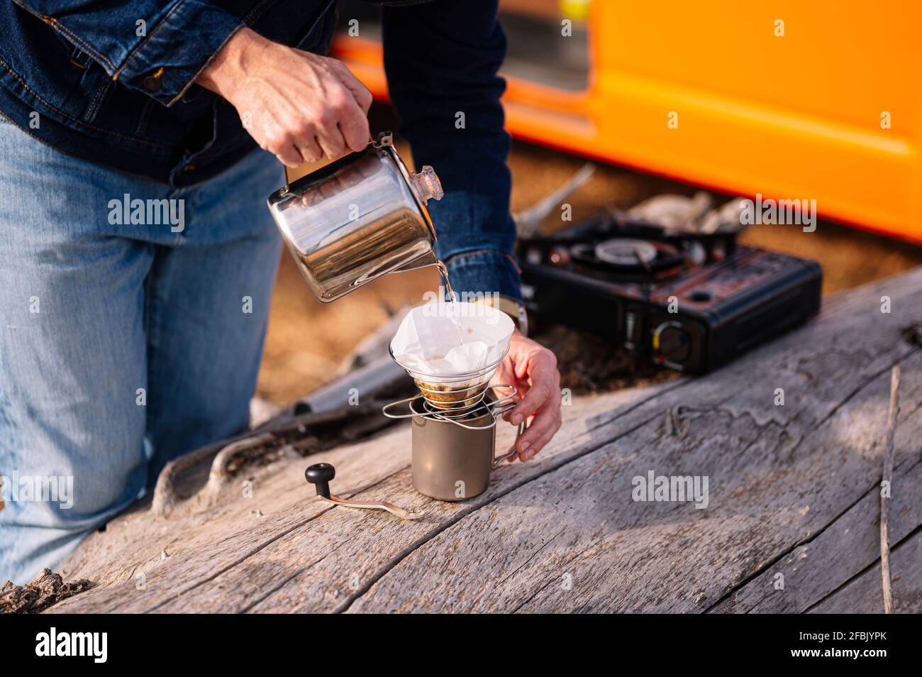 Man pouring water in mug through kettle during camping Stock Photo