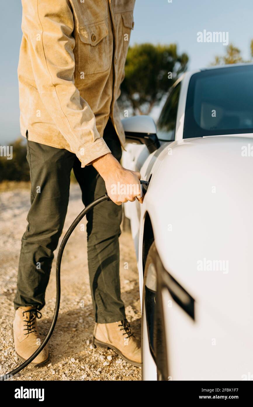 Man charging electric car during road trip Stock Photo Alamy