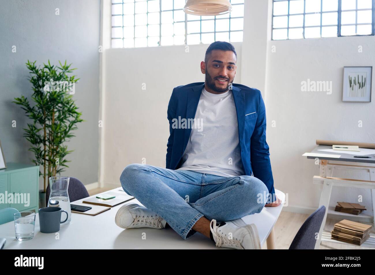 Businessman with cross-legged sitting on desk at office Stock Photo - Alamy