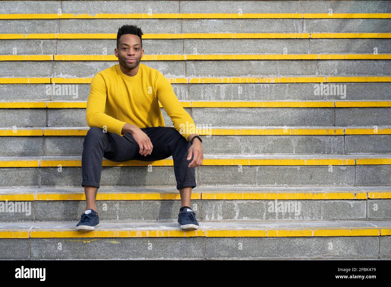 Relaxed man sitting on yellow staircase Stock Photo
