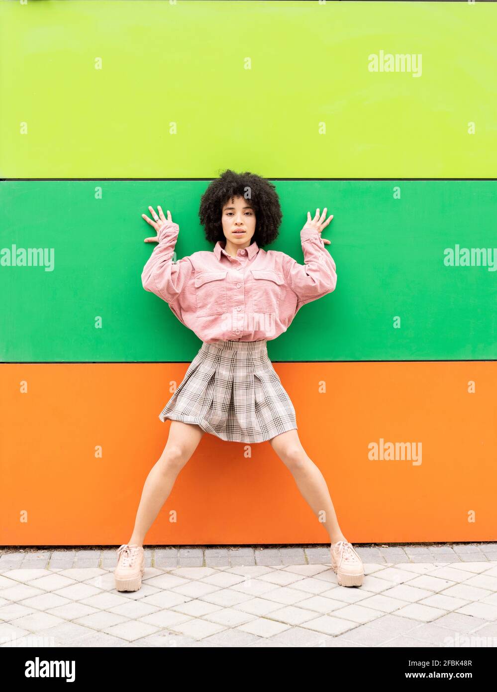 Young woman leaning on multi colored wall Stock Photo