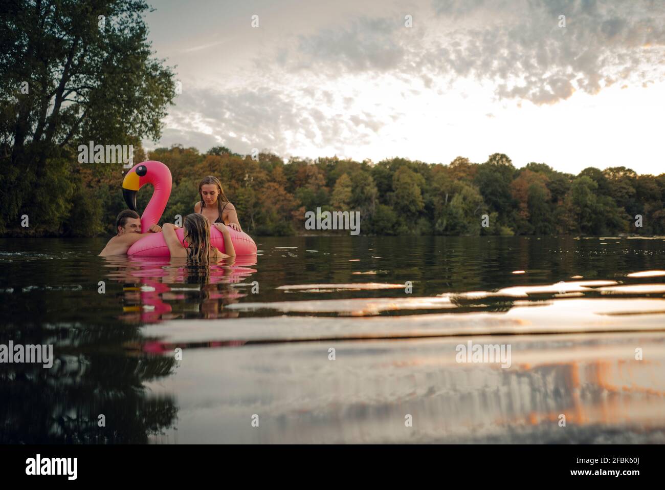 Young couple swimming in lake, kissing at sunset Stock Photo