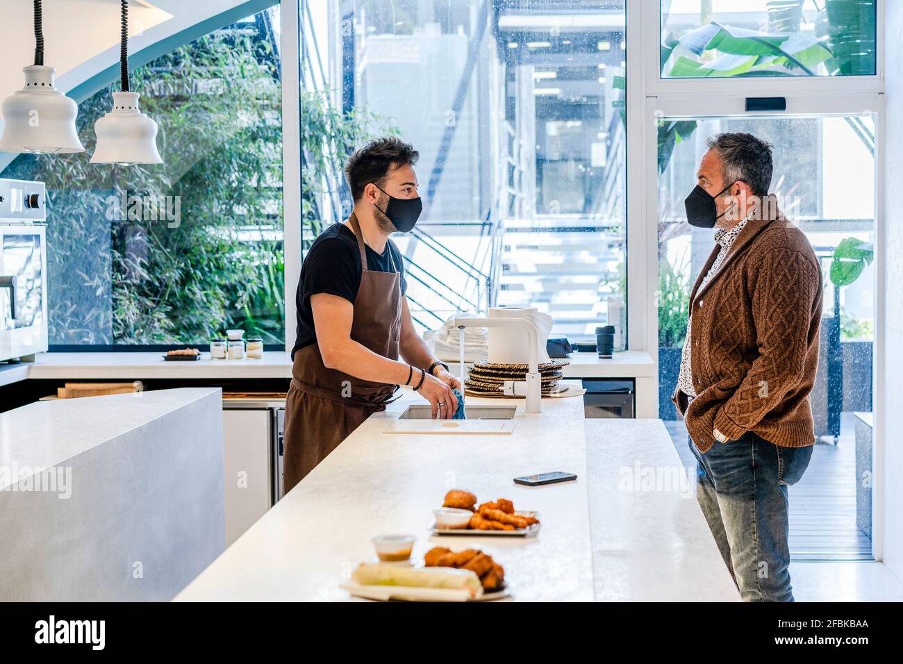 Chef with protective face mask looking at customer in restaurant during COVID19 Stock Photo Alamy