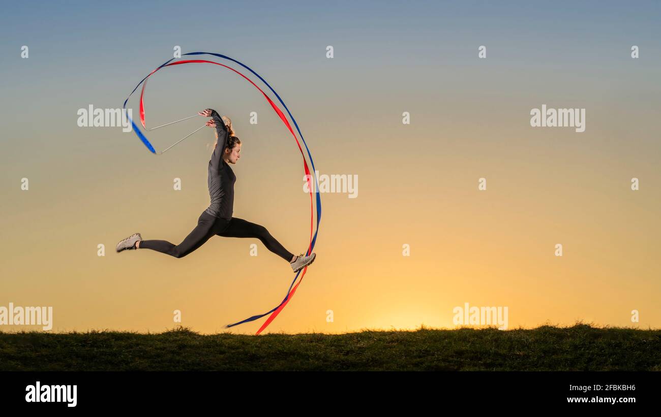 Sportswoman doing aerobics with ribbons during sunset Stock Photo